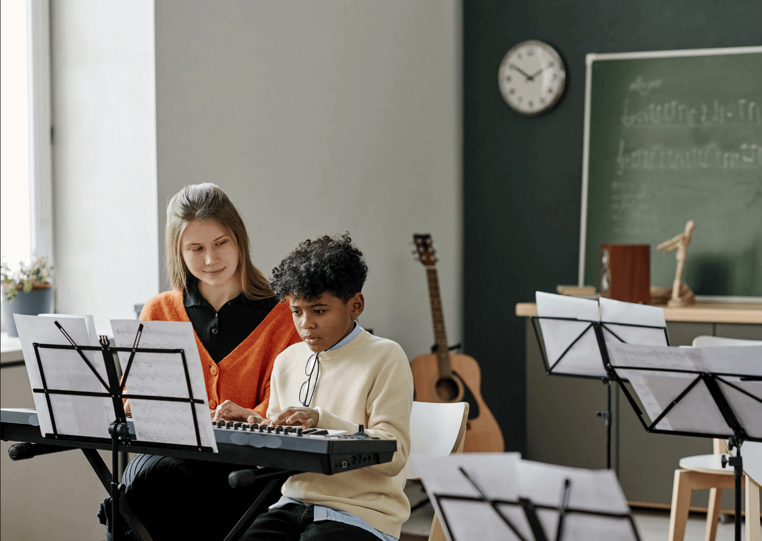 Lärare vägleder en ung elev vid keyboardet i vårt klassrum i Stockholm